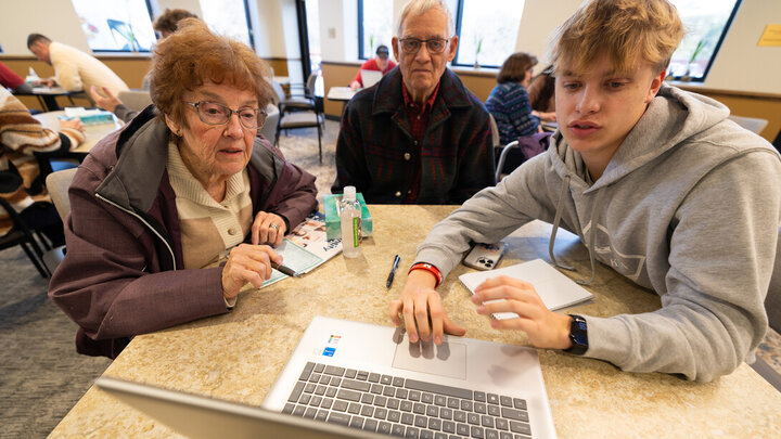 Cooper Sorensen, a first-year student studying business administration, shows Patti and Jim Wood how to navigate Windows 11 on their laptop. Sorensen volunteered for the monthly event held by the University of Nebraska-Lincoln's Engage Lincoln program and Aging Partners with several other members of his fraternity, Sigma Alpha Epsilon.
