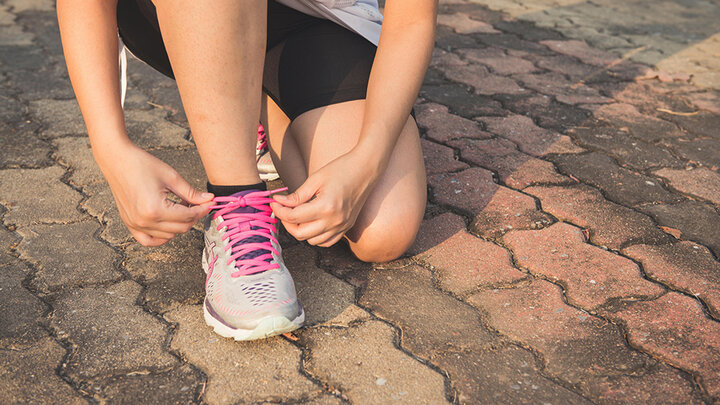 A person ties the laces on a running shoe [pexels]