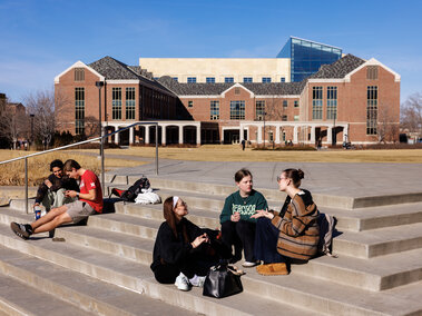 Groups of students sit on the steps near Broyhill Fountain on the Nebraska Union Plaza.