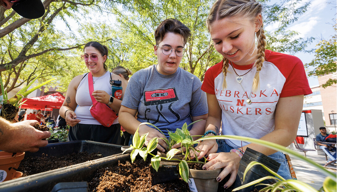 Shae Mitchell of Edison (center) and Emmy Oldham of Wellfleet add potting soil to the plants they received at the 2023 Well-being Fest. At left, Olivia Hanson of East Moline, Illinois, awaits her plant. [Craig Chandler | University Communication and Marketing]