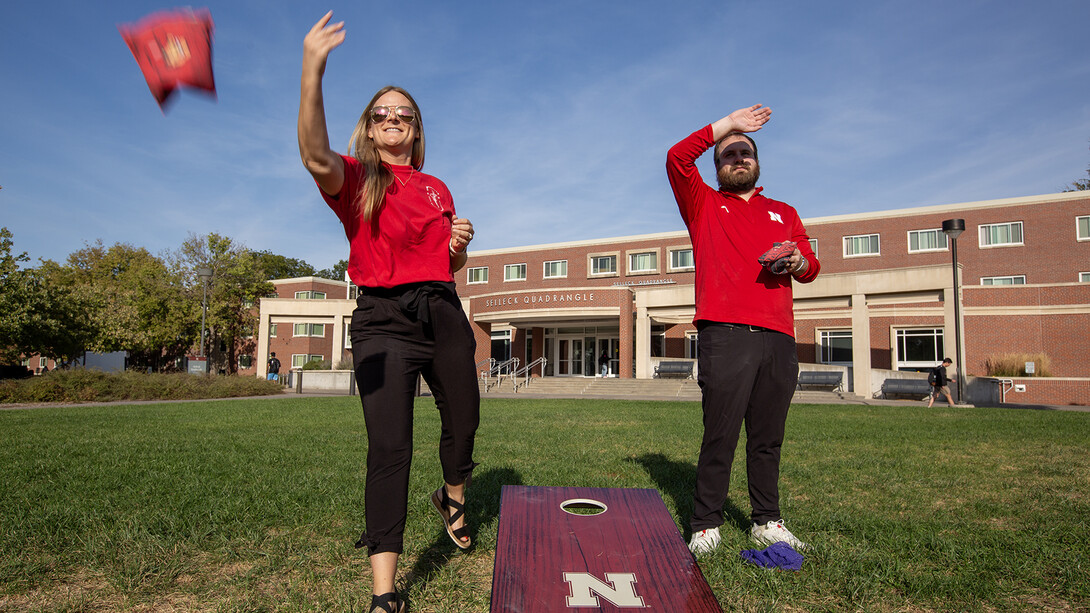 Nebraska's Hollie Swanson (left) and Logan Kahlor practice cornhole tosses while setting up the 2024 homecoming yard games competition on the Meier Commons. In her fifth year helping plan the annual celebration, Swanson is now leading the homecoming committee. [Troy Fedderson | University Communication and Marketing]