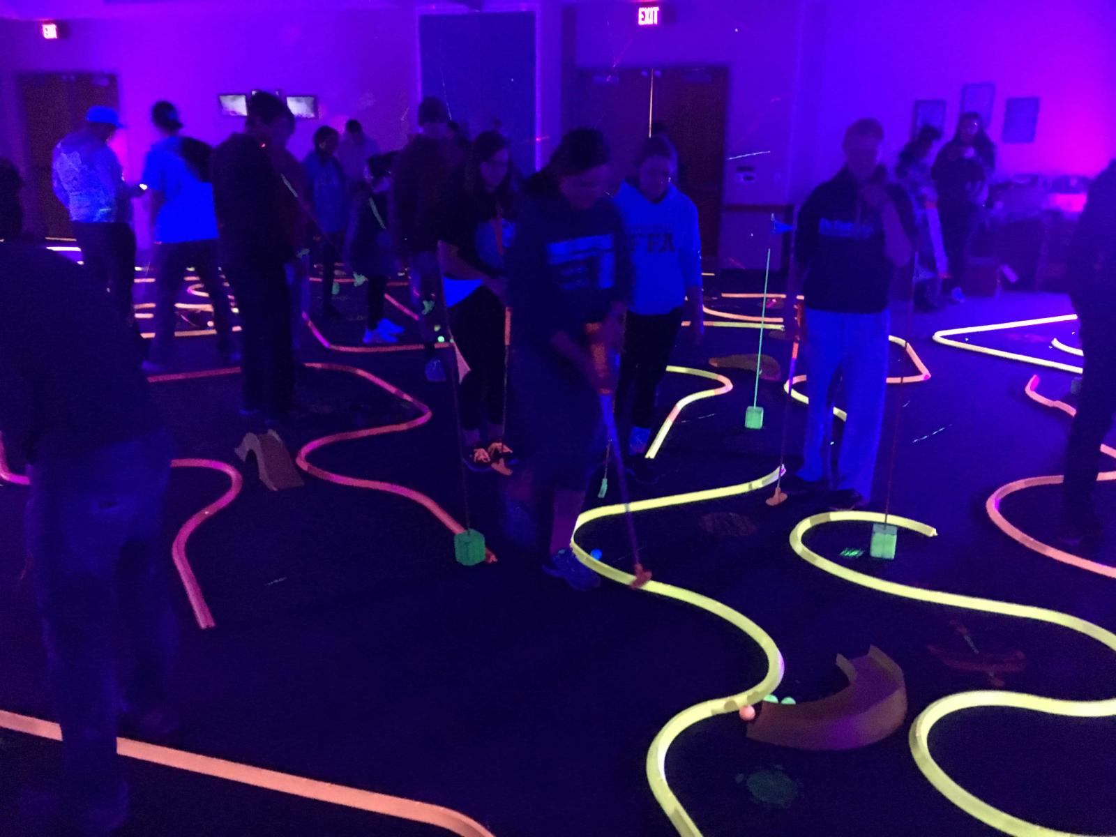 Students play glow golf under black lights in the Nebraska Union