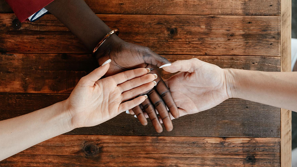 Hands rest one one another on a table