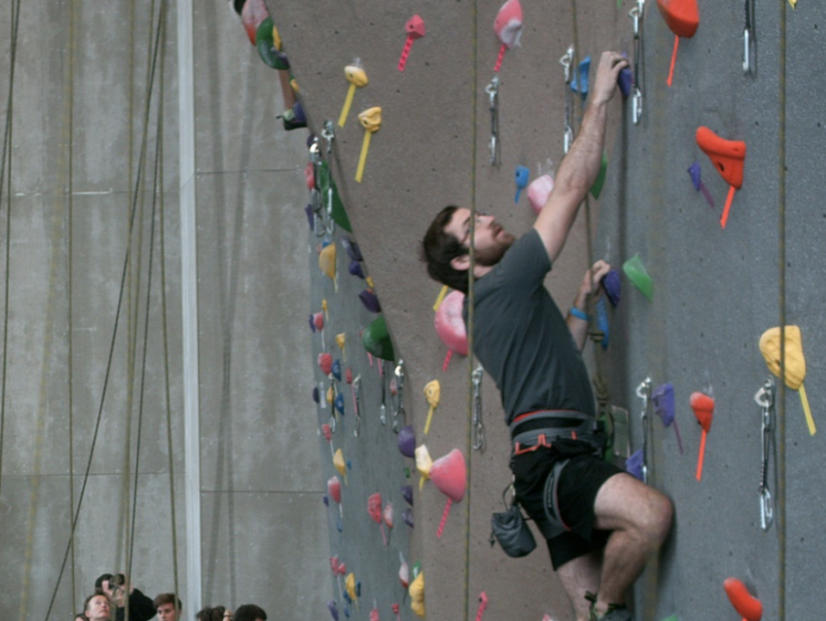 A climber scales teh climbing wall in the Outdoor Adventures Center.