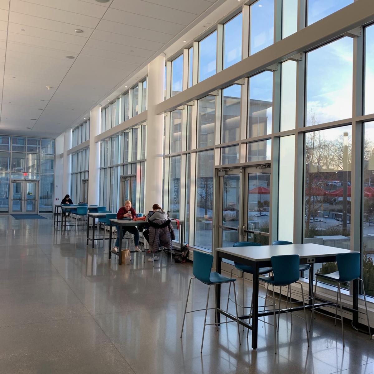 students studying beside large windows.