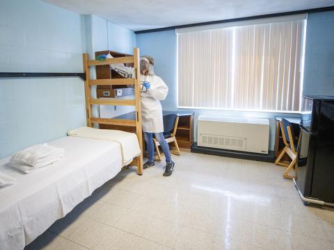 Cheryl Duncan, a residence hall custodial leader with University Housing, wears personal protective equipment as she demonstrates how the residence hall rooms will be cleaned. The face shield and Tyvek gown Duncan is wearing were manufactured at Nebraska Innovation Campus.