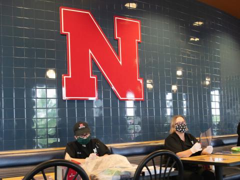 Dining Services employees (from left) Rochan Pinho, Janet Nichols and Dami Olsen assemble face shields at Harper Dining Center.