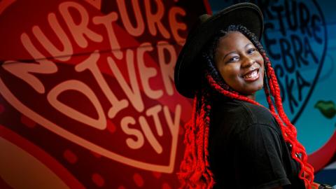 Alana Ross smiles for a photo in front of a mural in Anderson Hall. [Craig Chandler | University Communication and Marketing]