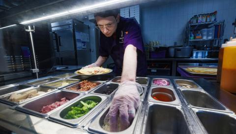 Kaine Splichal, dining service team leader, makes a gluten free pizza for a customer in Moxie’s Gluten-Free Café. The café is located inside Selleck Food Court.[Craig Chandler | University Communication and Marketing]