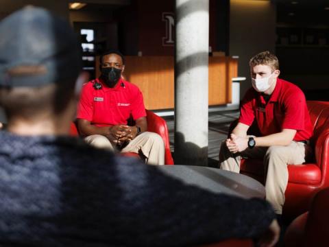 Community service officers Komlan Akakpo and Trevor Caldwell talk with Cohan Bonow, student and front desk supervisor at University Suites. The CSOs are wearing more casual uniforms in 2022.