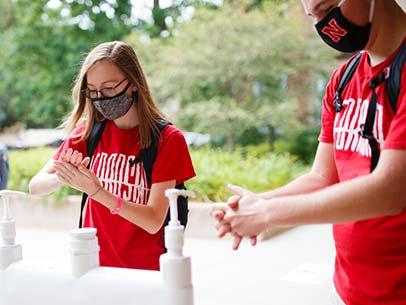 Students use hand sanitizer