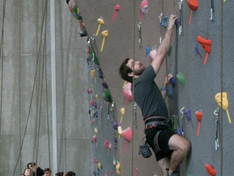 A climber scales teh climbing wall in the Outdoor Adventures Center.