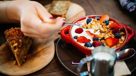 Diner eats yogurt, oats, blueberries, and strawberries